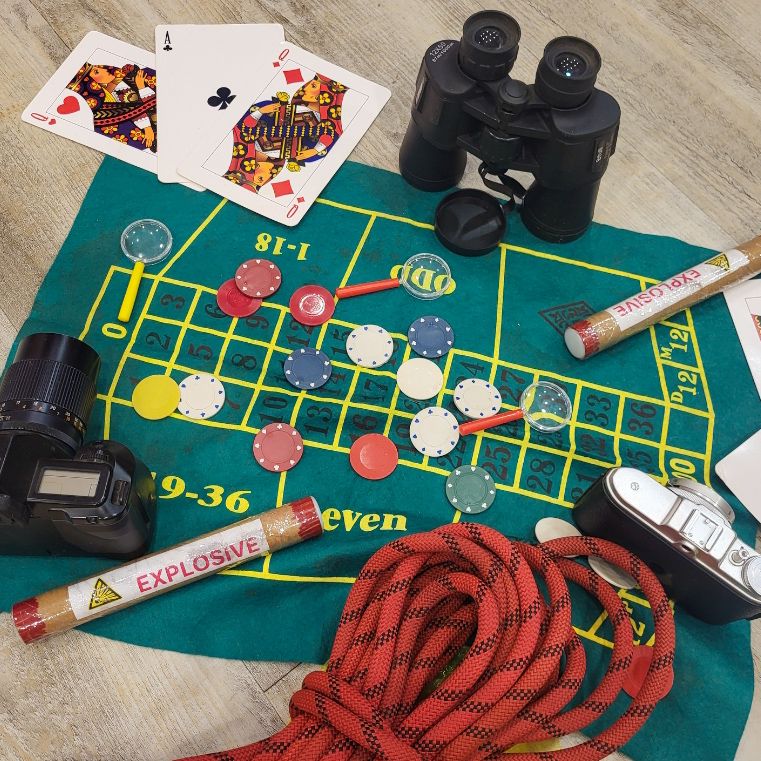 Das Bild Gegenstände wie Fernglas, Fotokamera, Seil, Sprengstoff, Spielkarten - Szene einer Agentenstory.